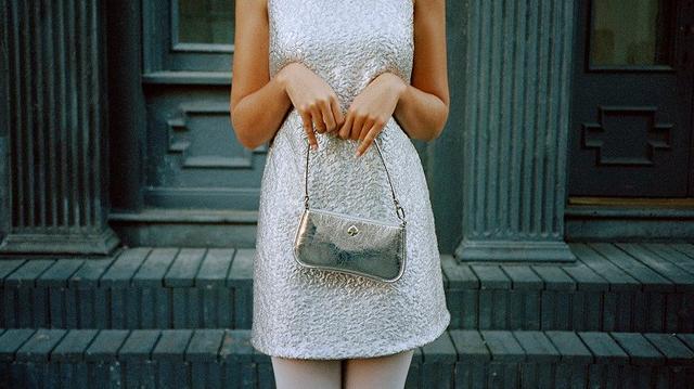 Women in sliver dress holding a metallic color bag