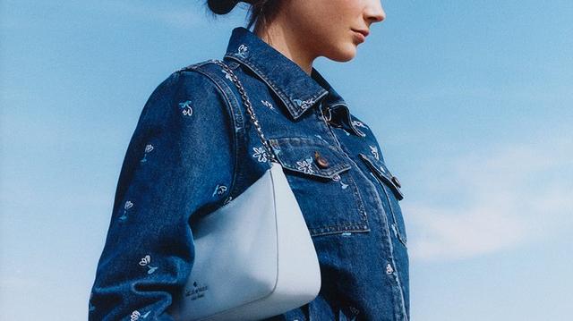 Two women modeling shoulder bags with chain straps, one beige and one light blue.