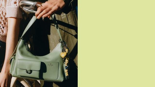 a green purse hanging from a handbag hook on a wall