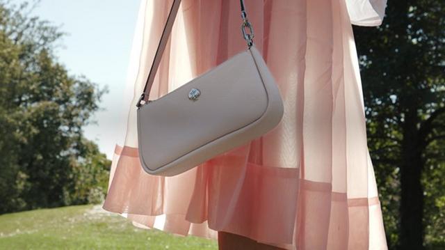 a white purse hanging from a pink dress in a park