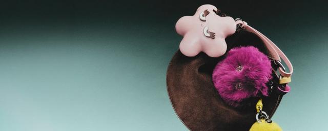 Brown velvet jewelry dish with pink flower-shaped dish, magenta fur pom-pom keychain, and charms.