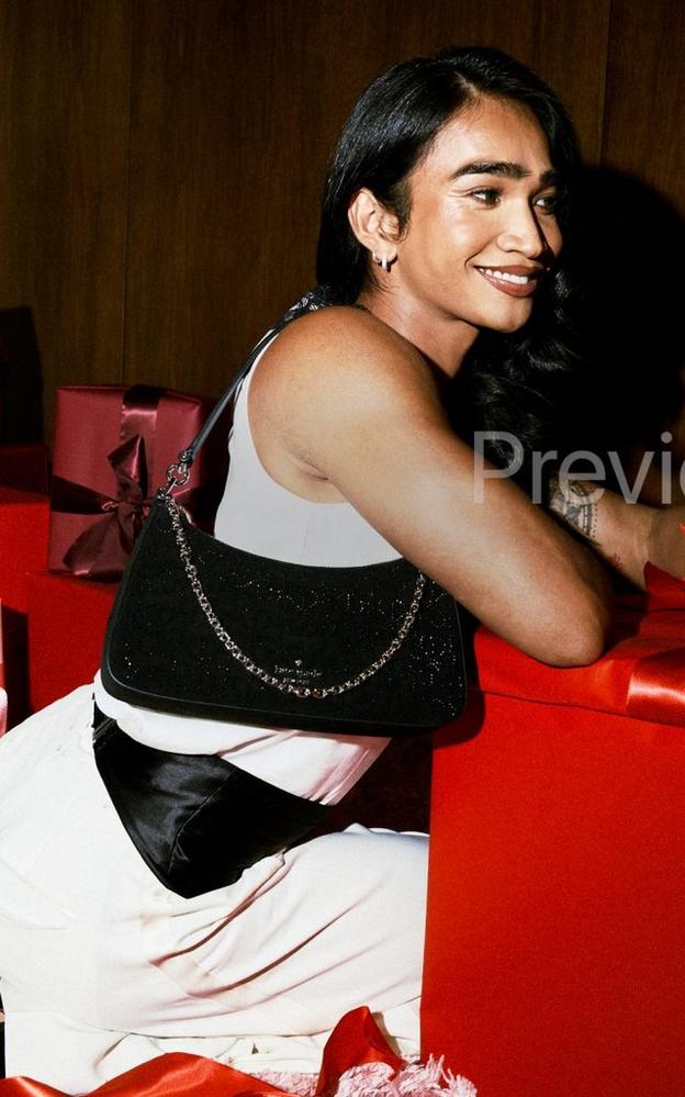 Woman in black and white outfit smiling while holding a speckled chicken surrounded by wrapped gift boxes.
