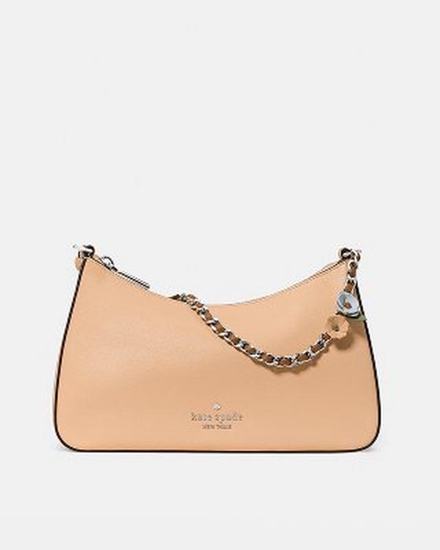 Beige kate spade new york shoulder bag with silver chain strap and decorative charm.