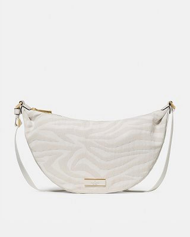 Cream quilted crescent-shaped shoulder bag with wave pattern and adjustable strap.