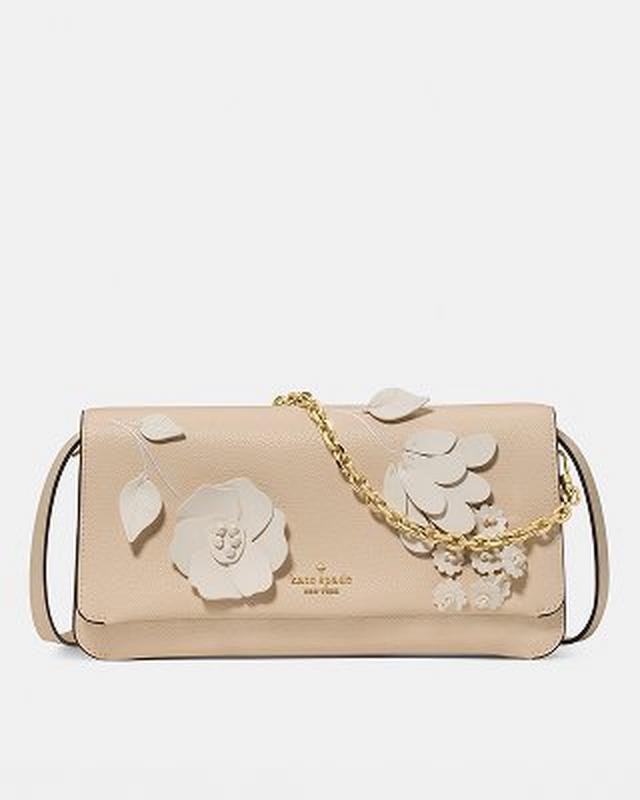 Kate Spade beige leather crossbody bag with white floral appliques and gold chain detail.
