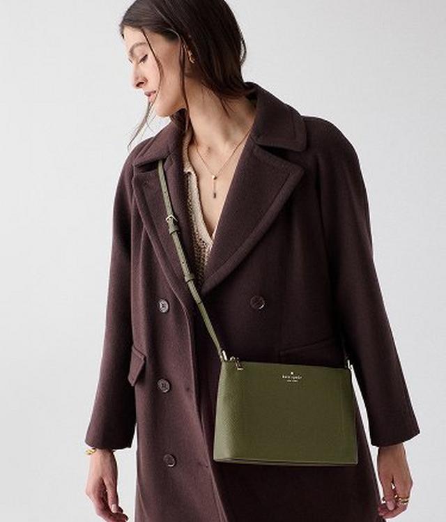 Woman wearing brown double-breasted coat with olive green Kate Spade crossbody bag and layered necklaces.