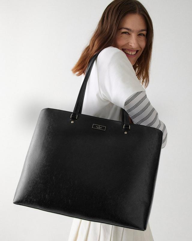 a woman is holding a large black bag in her hand