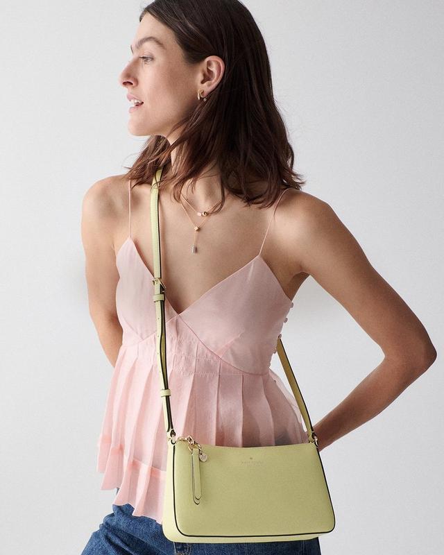 a woman in a pink top and a yellow cross body bag