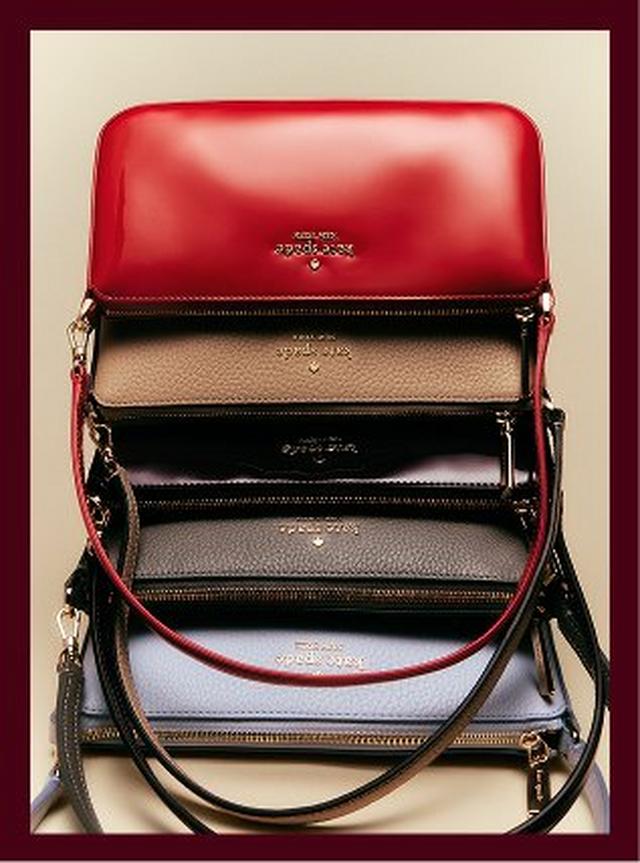 Kate Spade crossbody bags stacked in red, tan, black, gray, and white with gold hardware.
