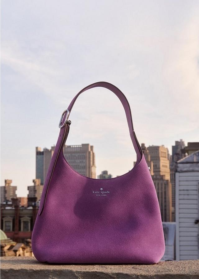 a purple purse sitting on top of a ledge overlooking a city