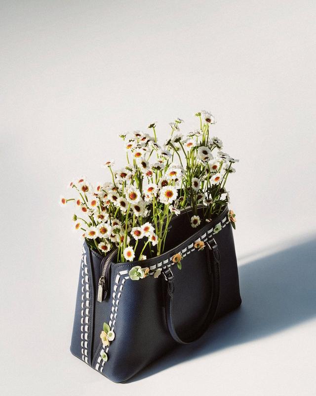 a purse with flowers in it on a table with a white background