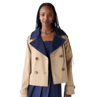Woman wearing a tan double-breasted jacket with navy blue collar and matching navy blue outfit underneath.